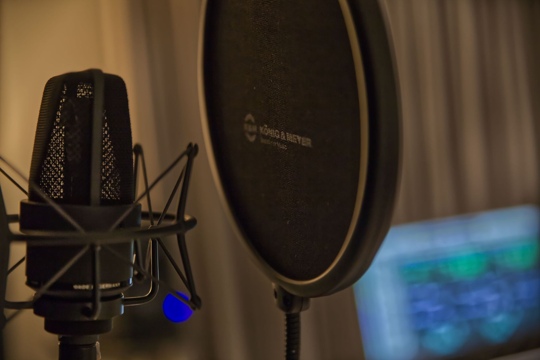 Close-up of a studio microphone and pop filter in a recording environment.