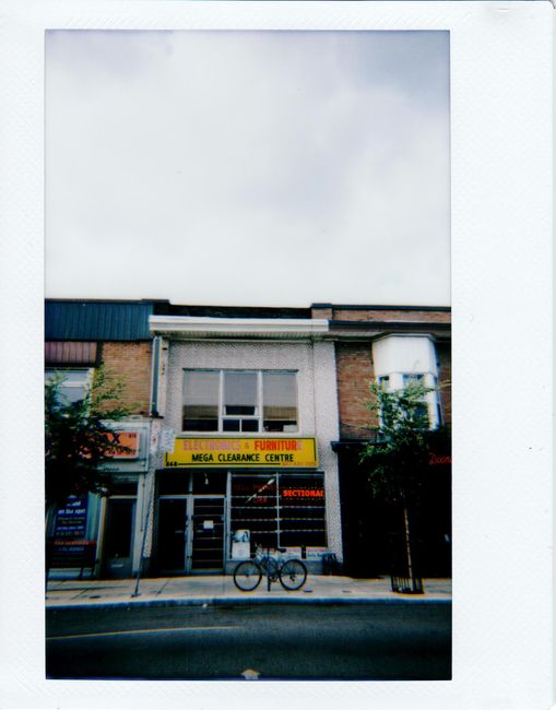 Charming Toronto storefronts line a street with a parked bicycle, featuring urban architecture.