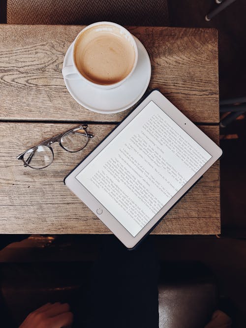 A person sitting at a table with a book and a cup of coffee