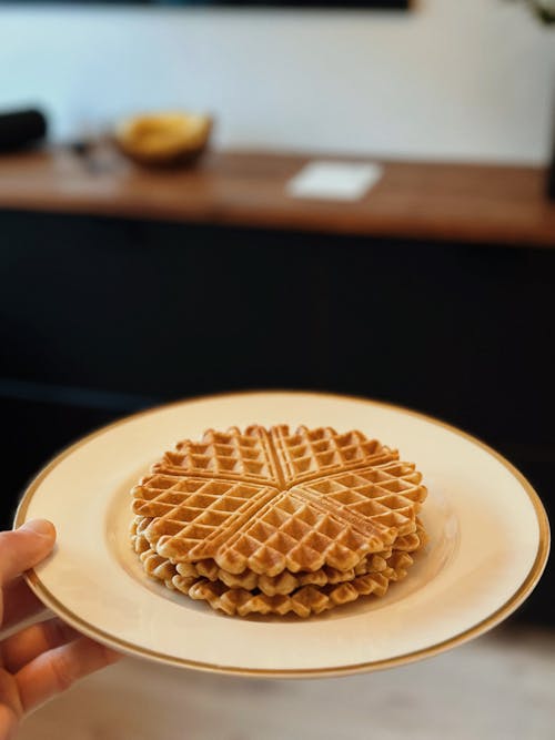 A person holding a plate with waffles on it