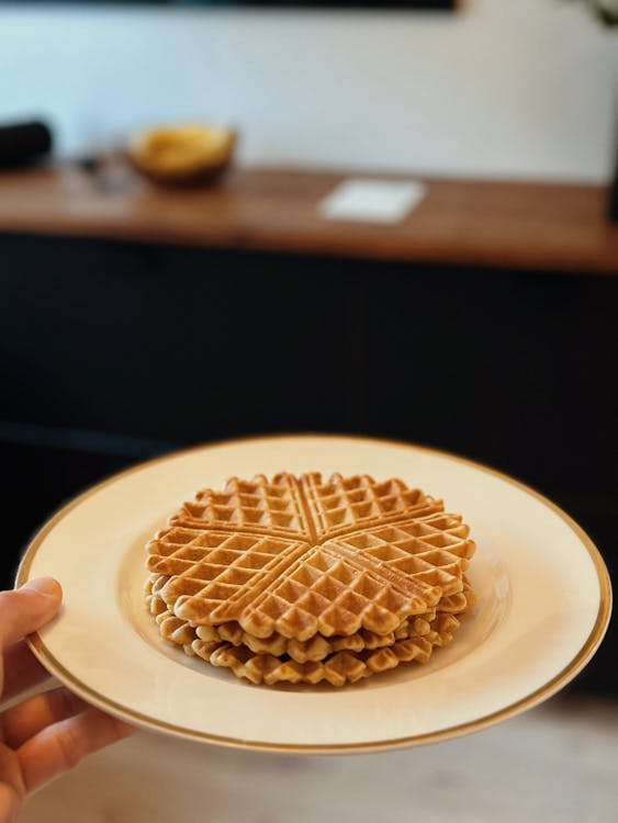 A person holding a plate with waffles on it