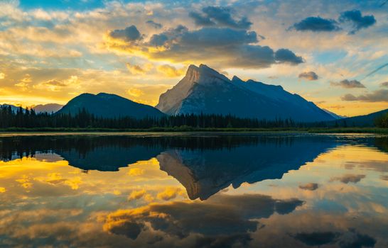 Stunning sunset reflection over mountains in Banff, Alberta, capturing vibrant colors in the lake.
