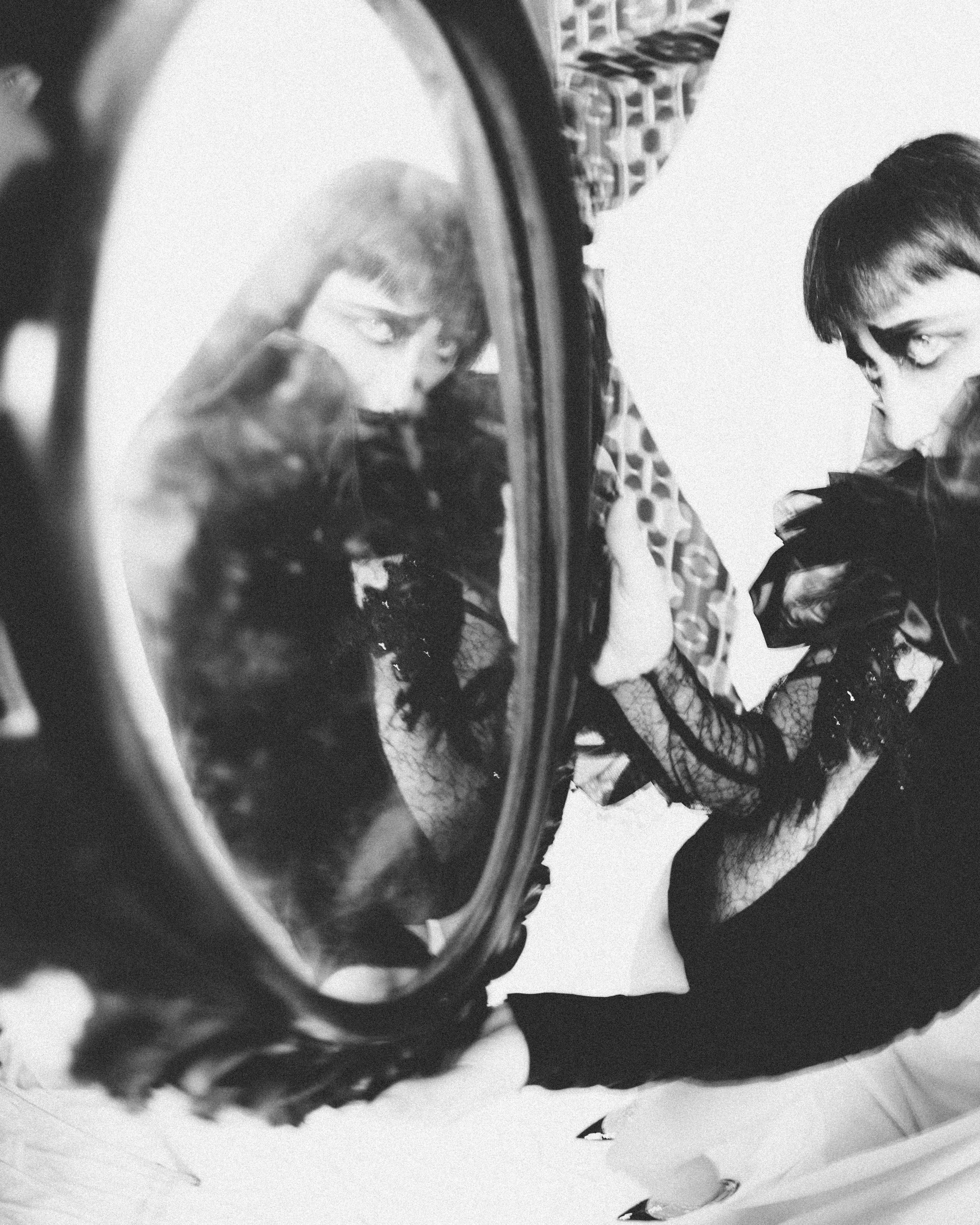 Vintage-inspired portrait of a woman reflecting in an oval mirror.