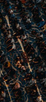 Overhead shot of a diverse group praying on a patterned carpet in a mosque.