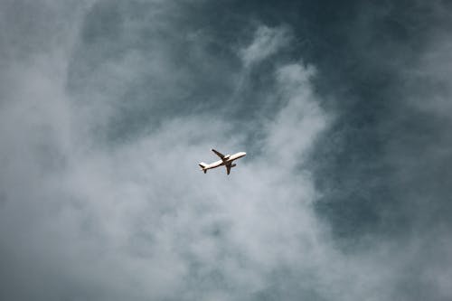 Белый самолет в воздухе под пасмурным небом