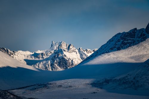 Free Scenic view of snowcapped mountains under a clear blue sky, bathed in winter sunlight. Stock Photo
