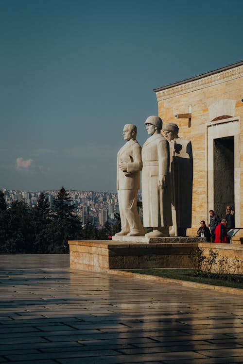 The statue of the three men is standing in front of a building