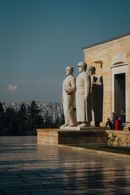 Free Statues in front of an urban landmark with cityscape view during daytime. Stock Photo