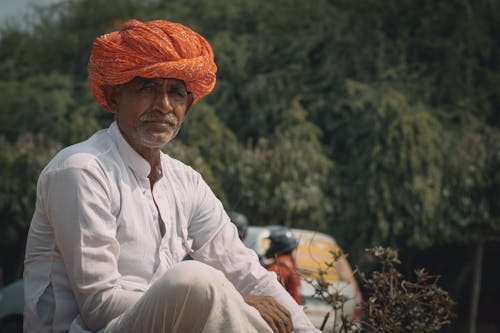 A man sitting on a bench wearing an orange turban