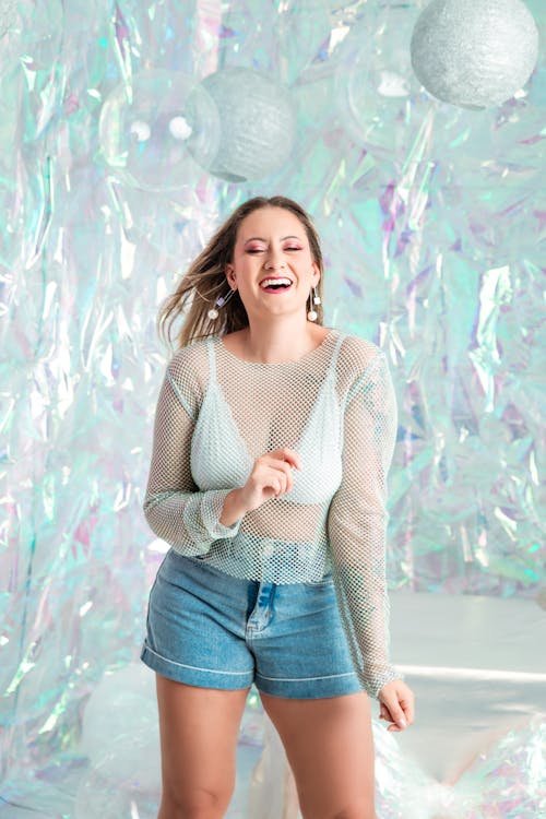 A woman in a short denim shirt and shorts is smiling