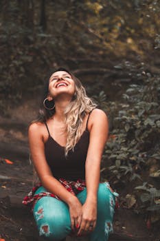 白天，一位穿着休闲服装的女人在郁郁葱葱的森林里快乐地微笑着