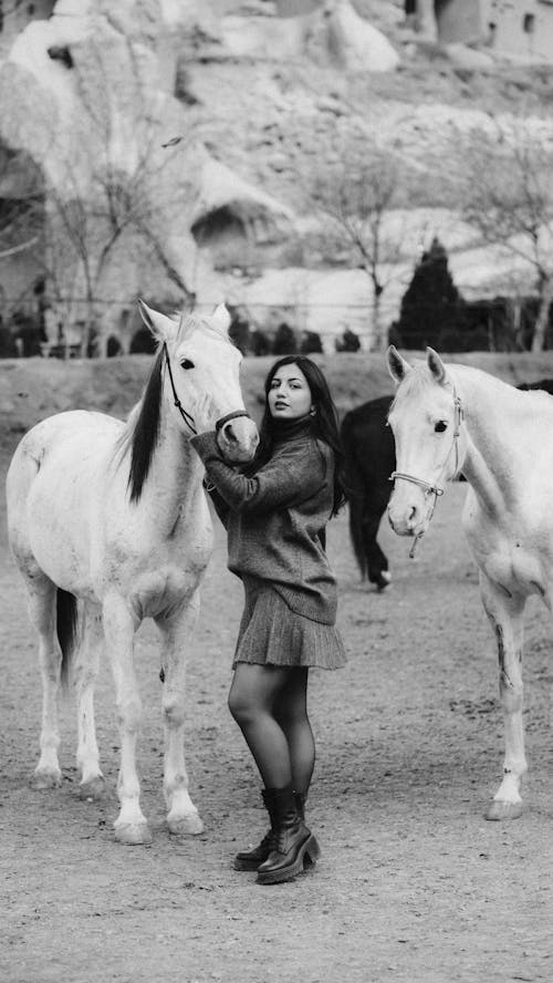 A woman is standing next to two horses
