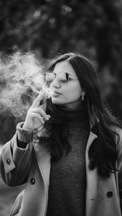 A woman smoking a cigarette in black and white
