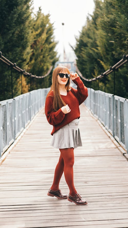 A woman in red sweater and tights standing on a bridge