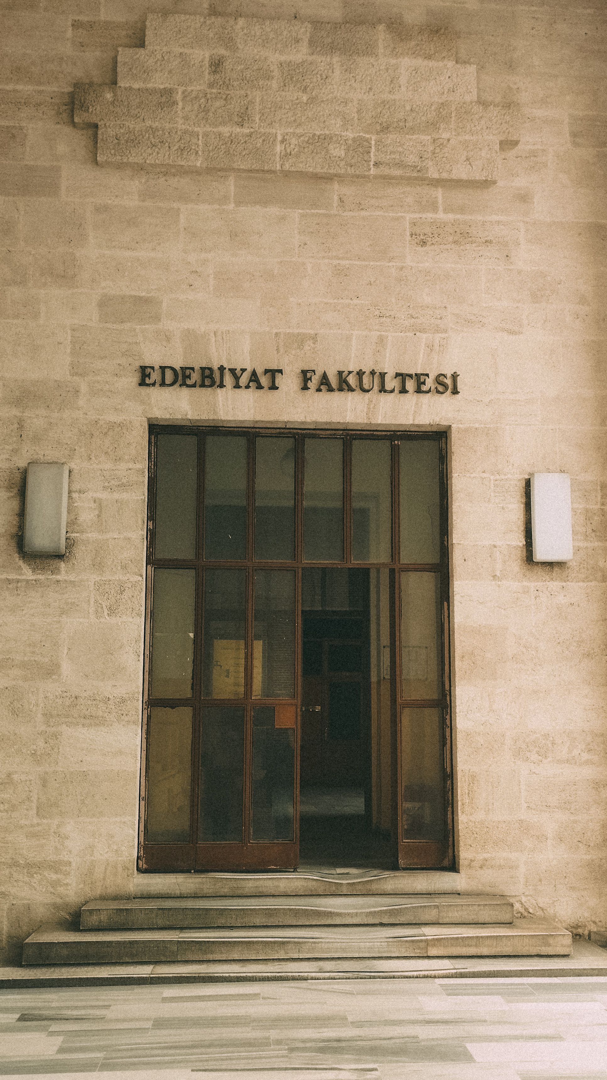 Entrance to a historic university faculty building with stone facade and wooden door.