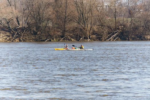 Three kayakers enjoy a peaceful ride on a Warsaw lake surrounded by autumn trees.