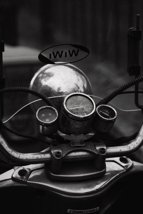 Free A close-up of a vintage motorcycle dashboard with gauges and emblem in a moody black and white setting. Stock Photo
