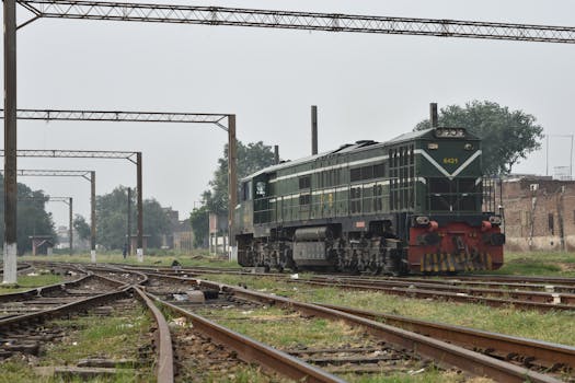 A green locomotive on railway tracks in an outdoor setting with overhead wires.