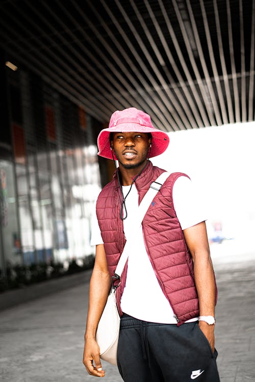 Young Man in a Casual Outfit in a Pink Hat under a Modern Building