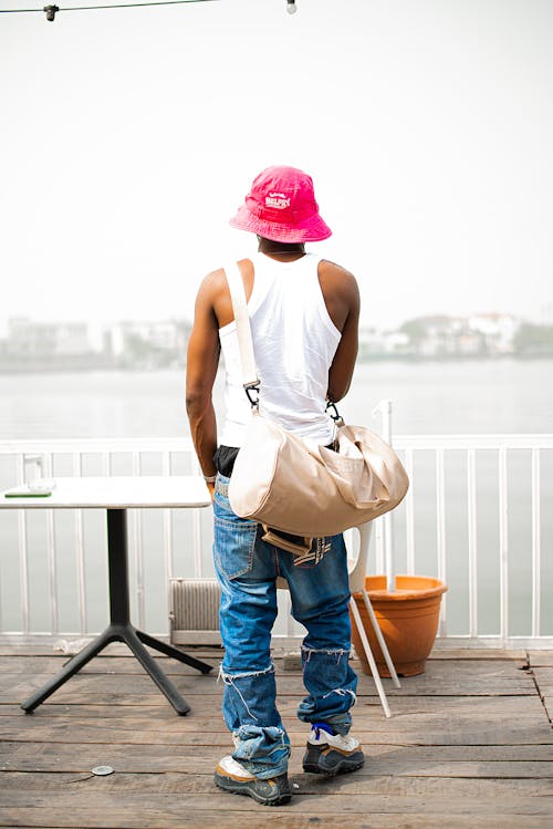 A man in a hat and jeans standing on a dock