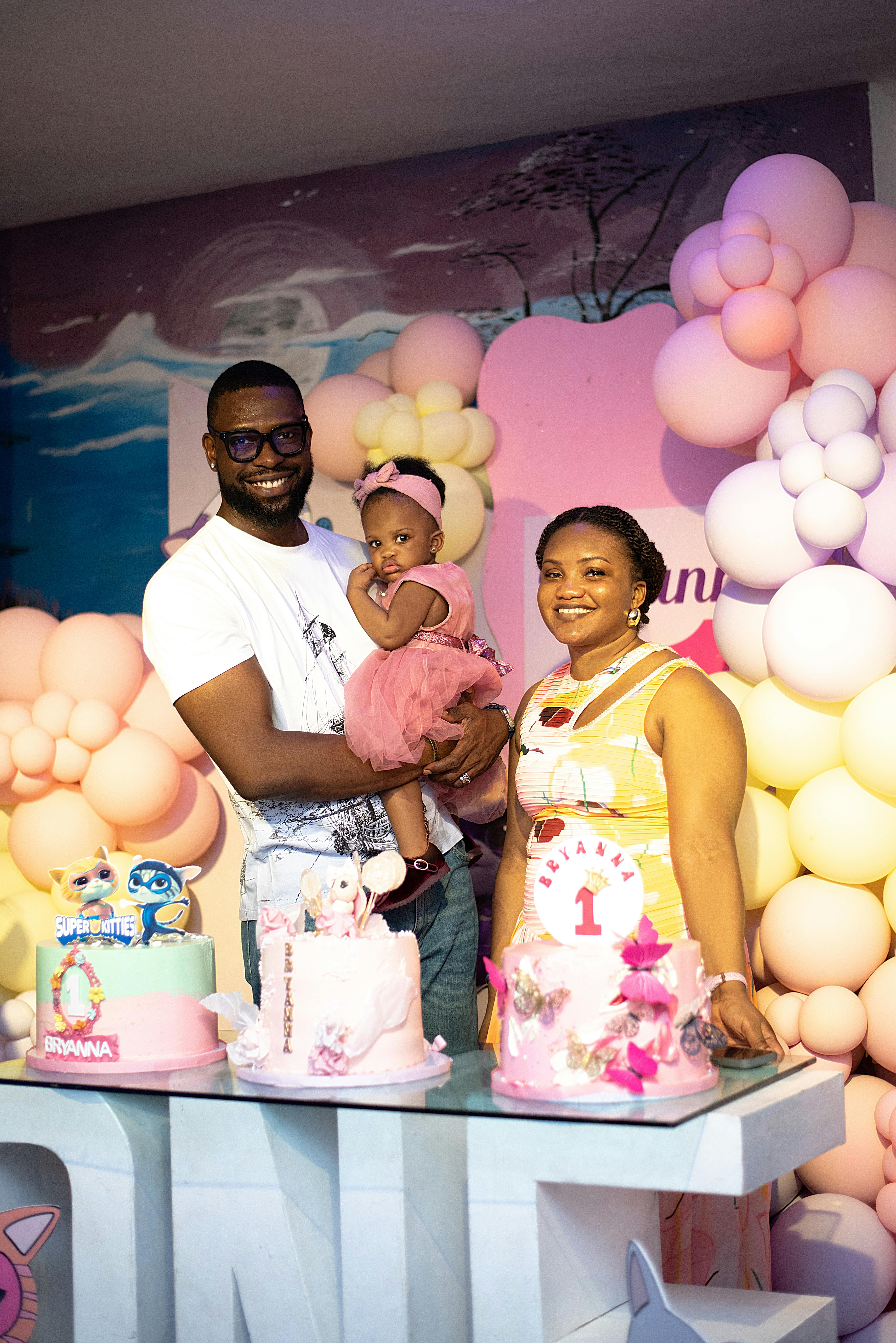 Happy family celebrating a child's birthday with colorful cakes and balloons.