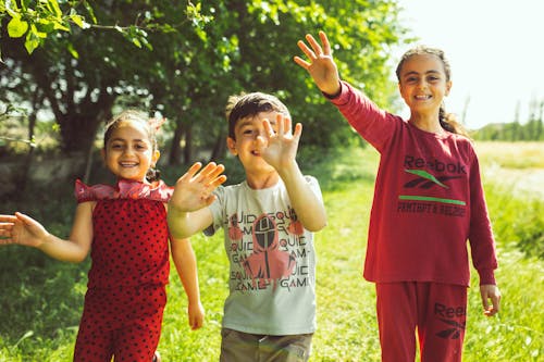 Two Girls and a Boy Waving and Smiling at the Hayfield