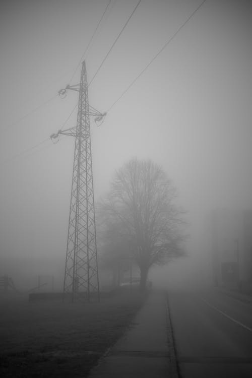 A black and white photo of a power pole in the fog