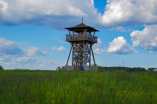 A tower in a grassy field with clouds in the sky