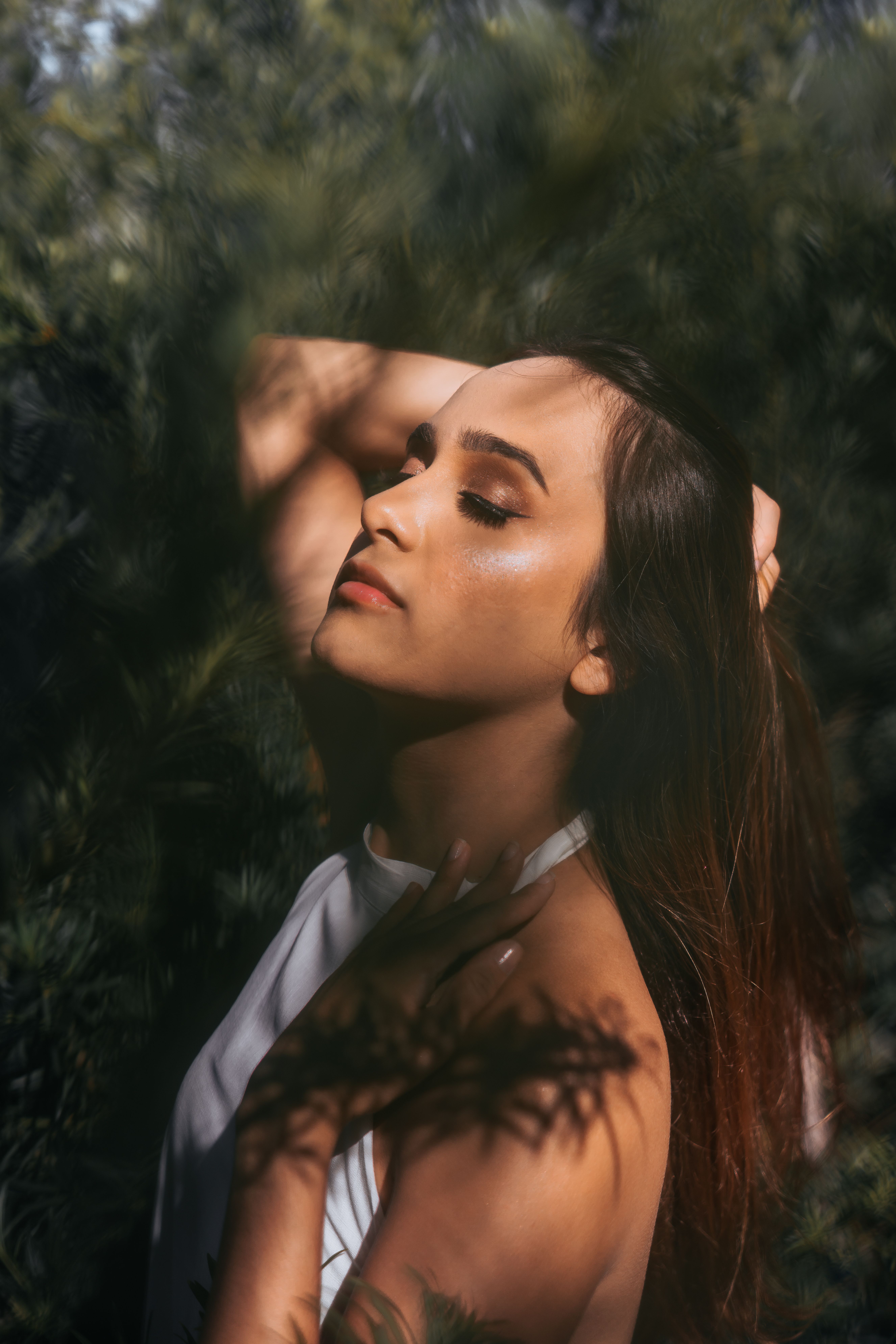 Serene portrait of a young woman enjoying sunlight in a lush green park.
