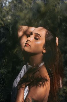 Serene portrait of a young woman enjoying sunlight in a lush green park.