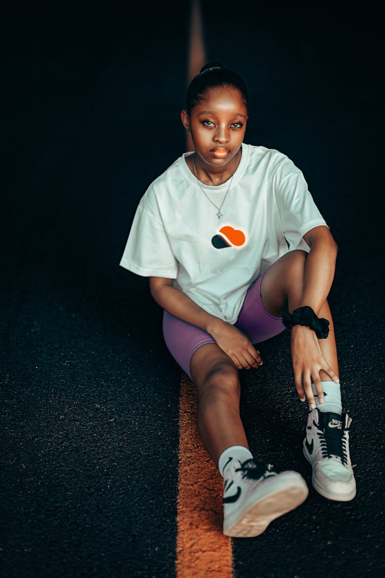 Young Woman In A Trendy Outfit Sitting On A Street 