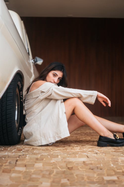 A woman sitting on the floor next to a car