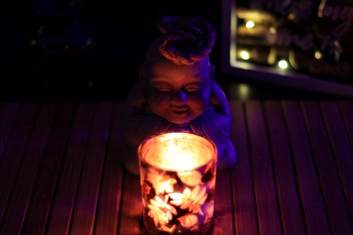 Free Close-up of a Buddha figurine illuminated by a candle in a peaceful night setting. Stock Photo