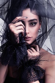 Captivating portrait of a woman with striking makeup and a black tulle veil, showcasing elegance and mystery.