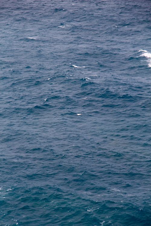 Free Aerial view of calm ocean waves with sunlight glistening on the water surface. Stock Photo