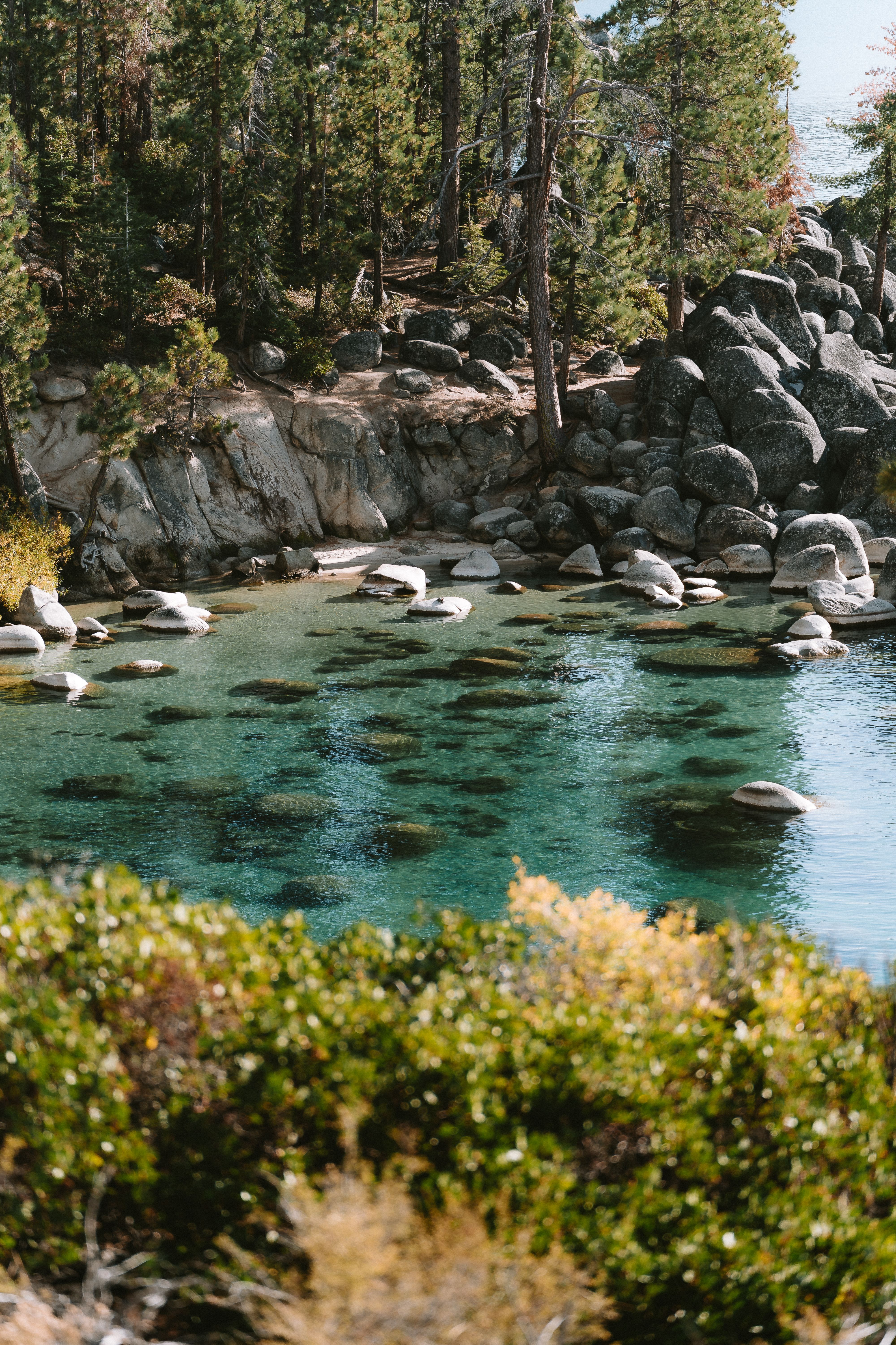 A lake surrounded by trees and rocks · Free Stock Photo