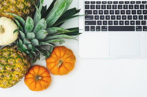 Free Pumpkins and Pineapple Next to Laptop Stock Photo