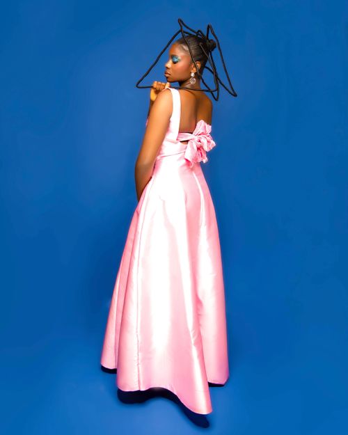 Free Stylish model in pink gown and geometric hat against blue backdrop. Stock Photo