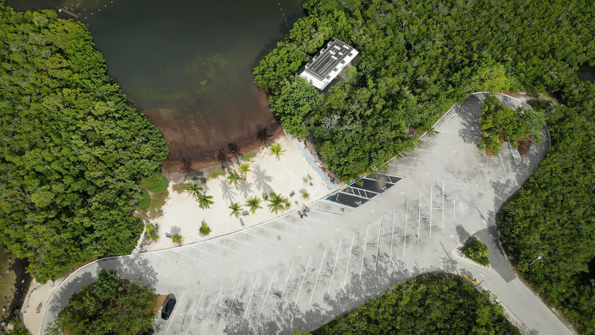A stunning aerial view of a parking lot next to a beach surrounded by lush greenery in Everglades City, FL.