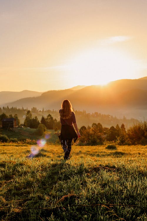 A woman walking through a field at sunset