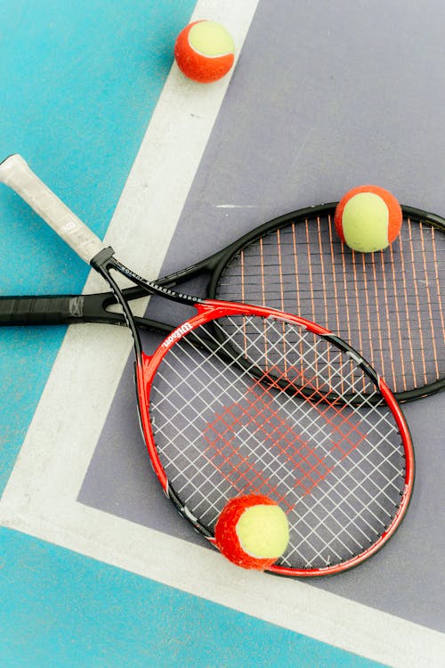 Pair of Tennis Rackets with Tennis Balls on Court · Free Stock Photo