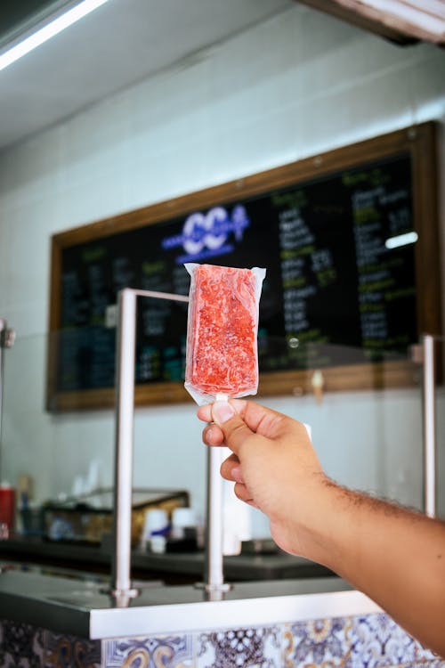 Hand Presenting an Ice Cream on a Stick in a Store