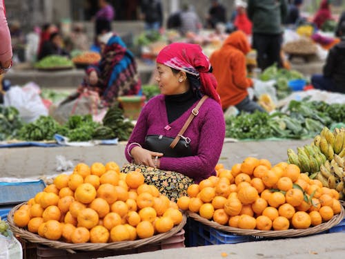 A woman is selling oranges at a market