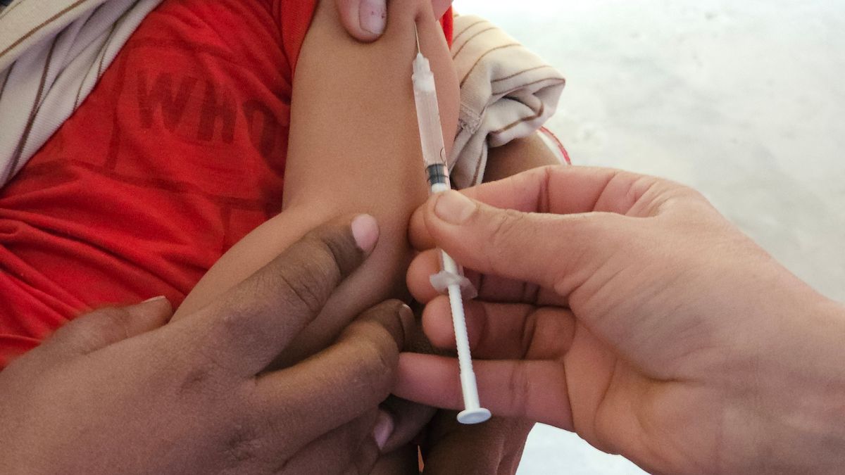 A child getting a vaccination shot administered by a healthcare professional indoors.