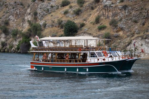 Free Scenic cruise boat sailing through mesmerizing Halfeti in Türkiye, offering a serene water experience. Stock Photo