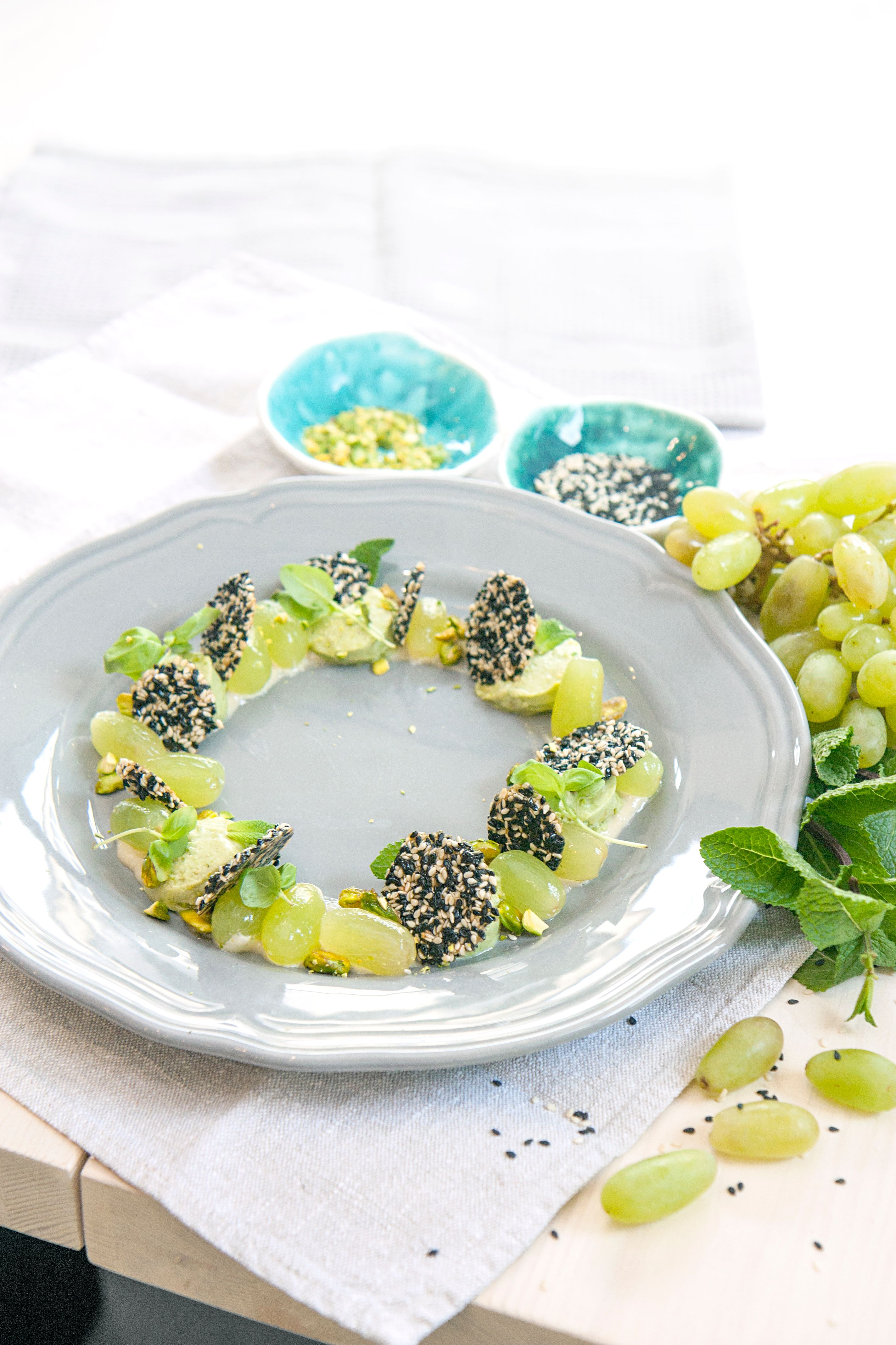 Artistic food arrangement featuring grapes and sesame encrusted cheese on a plate.