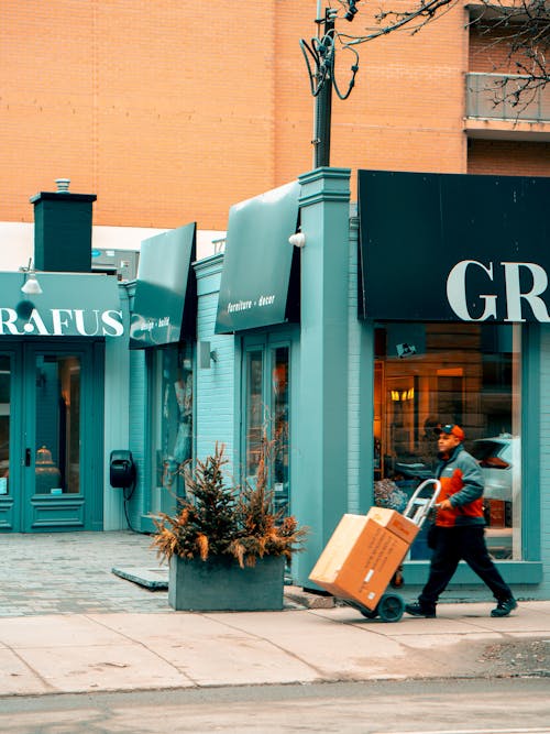 Man Pushing Hand Truck Beside Building