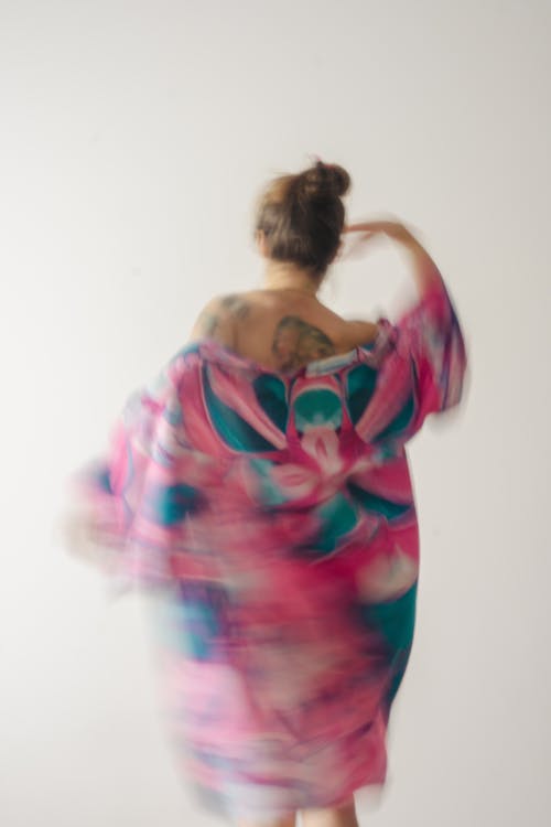 A woman in a pink and blue dress is walking