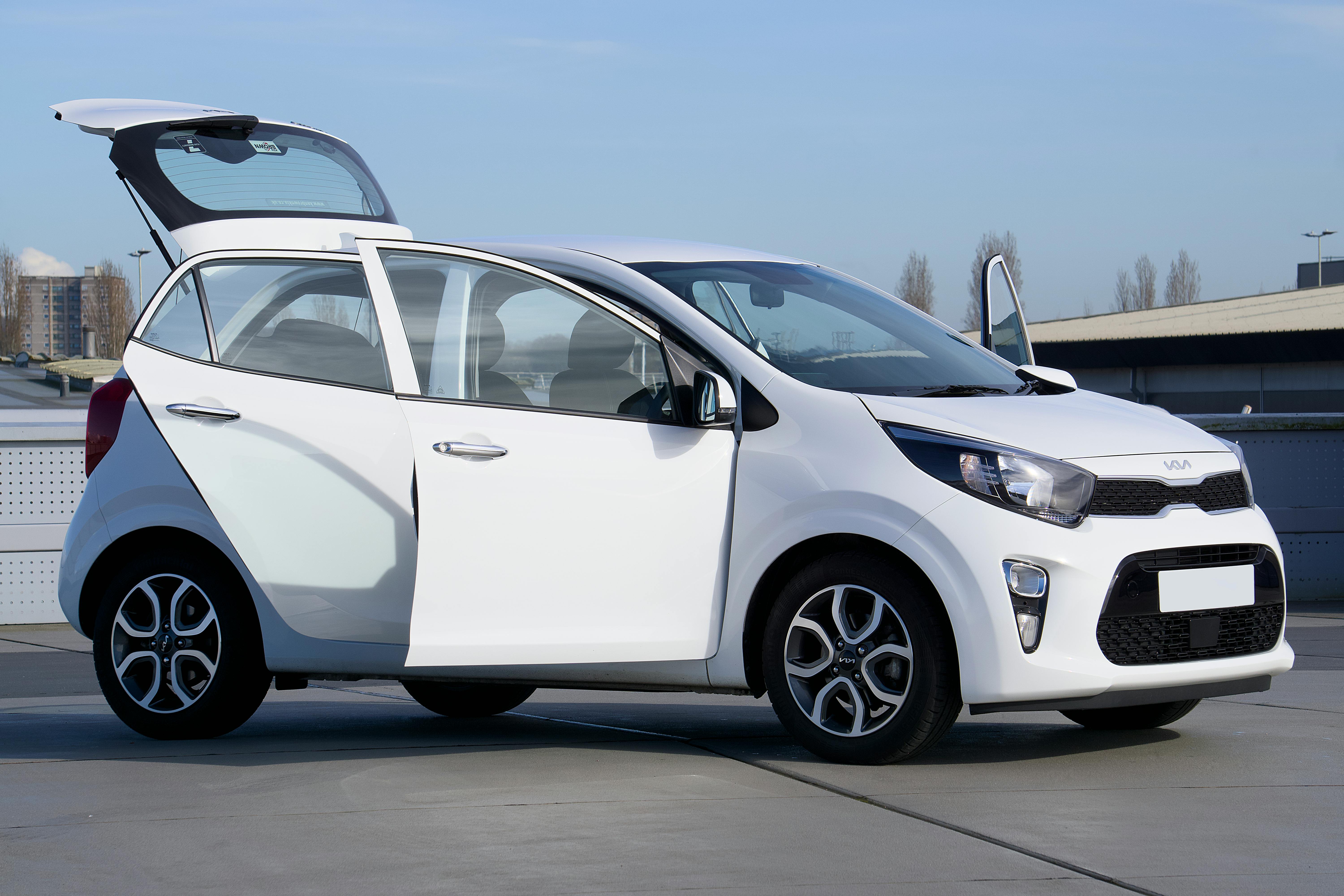 White Kia Picanto car with open doors parked outdoors in Harlow, England.