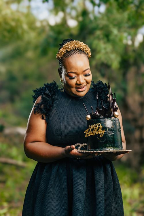 Free Woman in black dress holding an elegant birthday cake outdoors, embracing celebration and fashion. Stock Photo